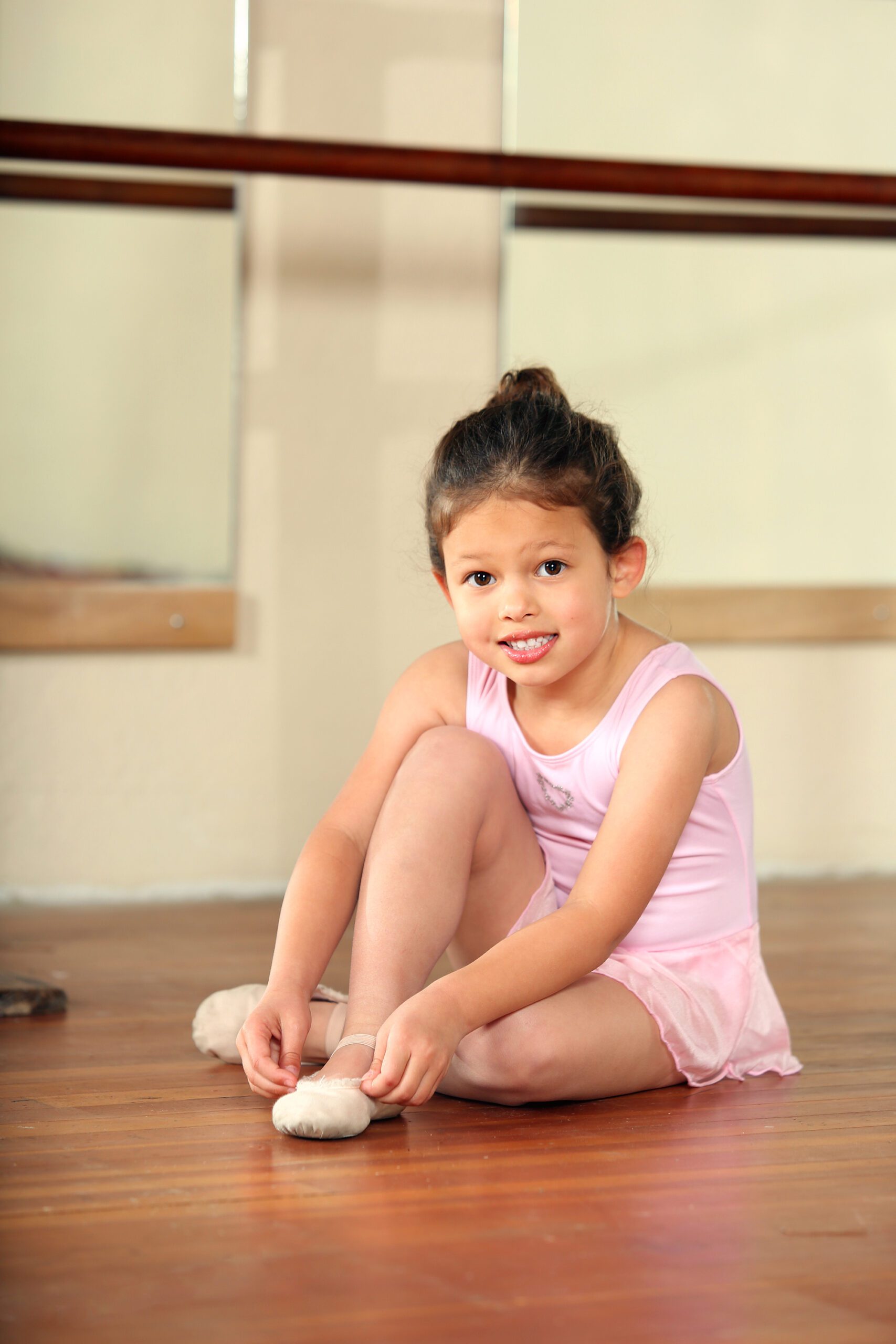 Cute Little Ballerina Adjusting Her Ballet Shoes