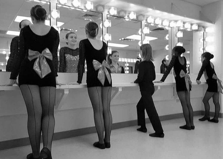 A Group of Women in Black Dresses With Bows on Their Back